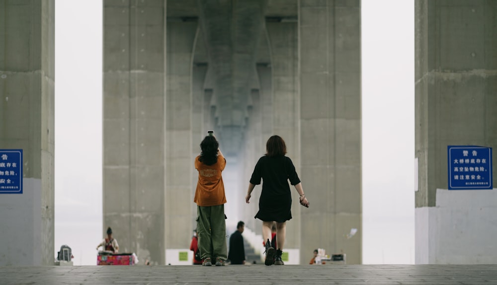 a couple of women walking across a bridge