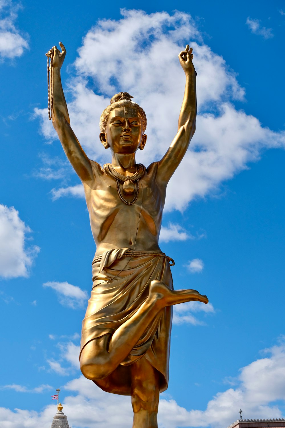 a golden statue of a man with his arms in the air