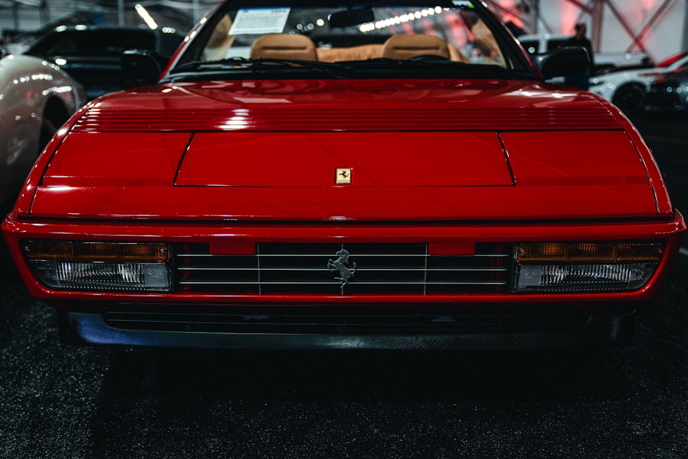 a red ferrari parked in a garage next to other cars