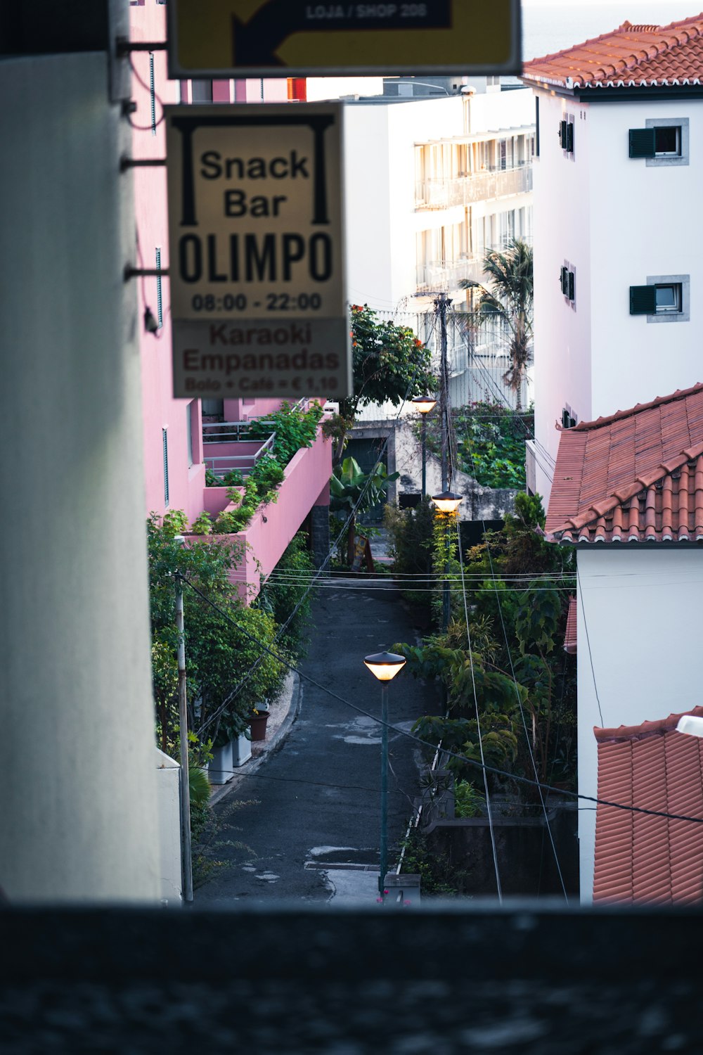 a view of a narrow street with a snack bar sign