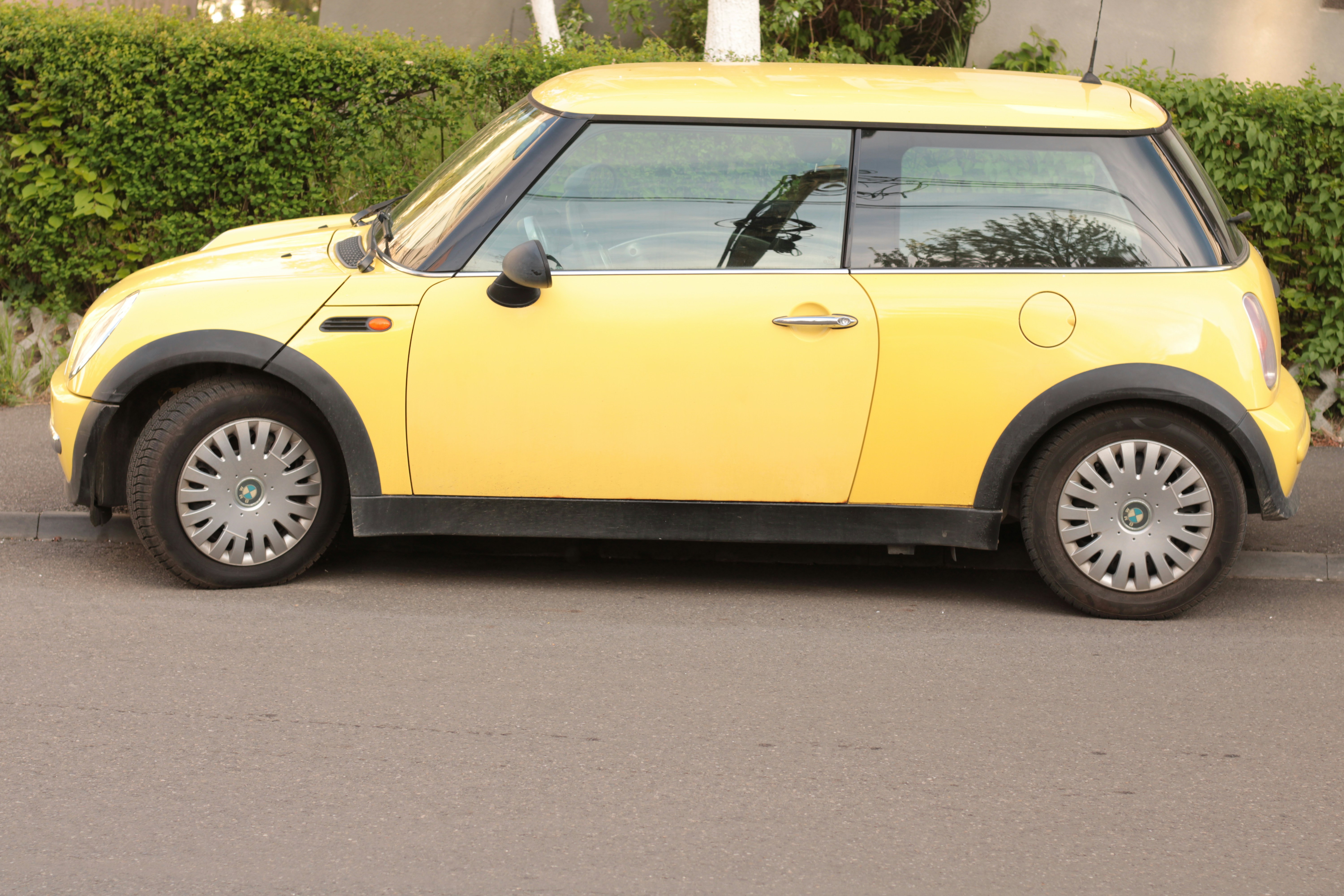 a small yellow car parked on the side of the road