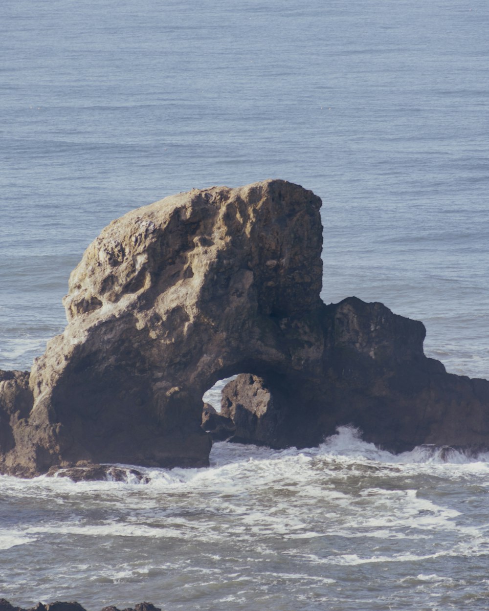 ein großer Felsen, der aus dem Meer ragt