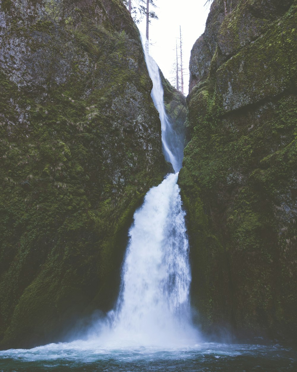 a large waterfall is coming down the side of a mountain