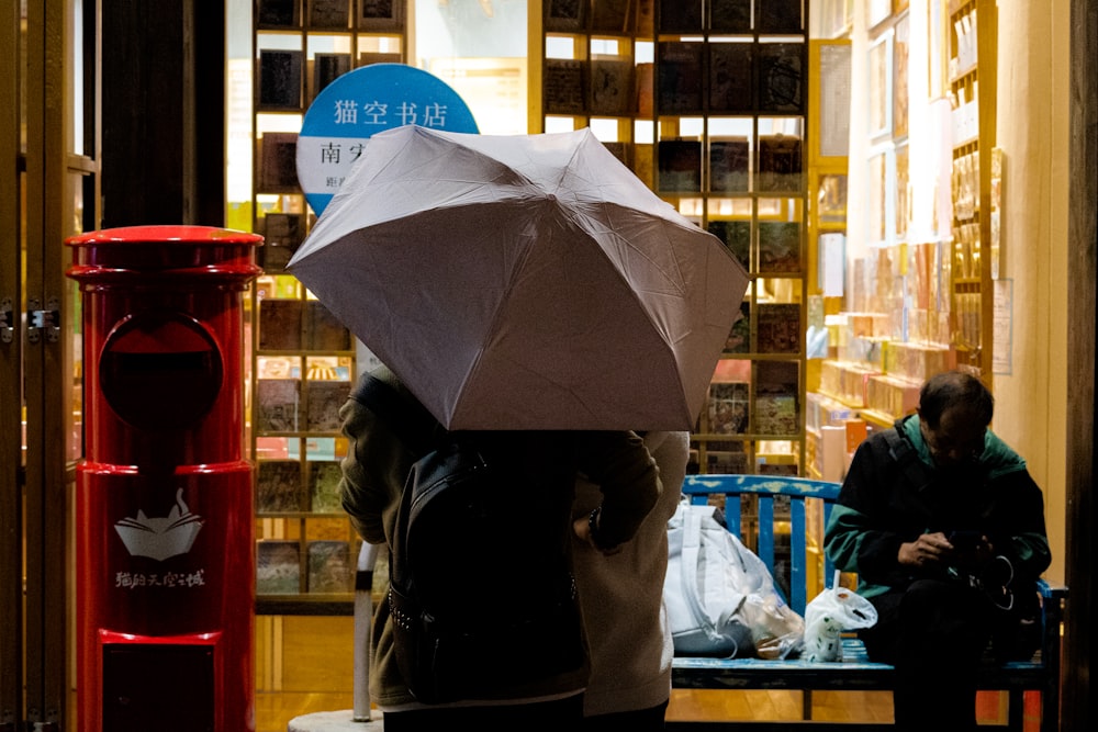 a person sitting on a bench with an umbrella