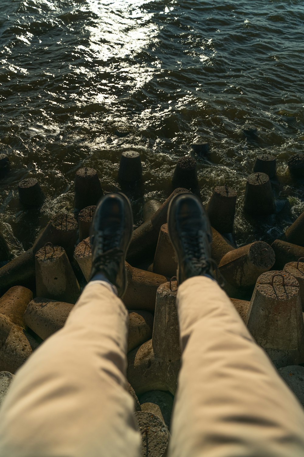 a person with their feet up on some rocks near the water