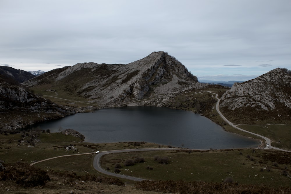 a road winding around a lake in the mountains