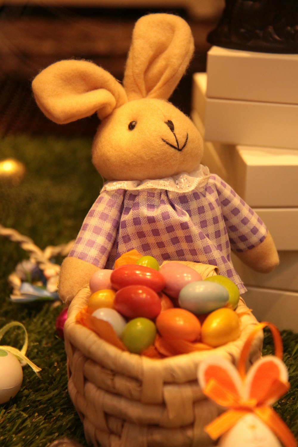 a stuffed rabbit sitting next to a basket of eggs