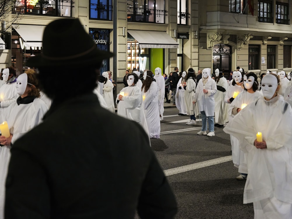 a group of people dressed in white walking down a street