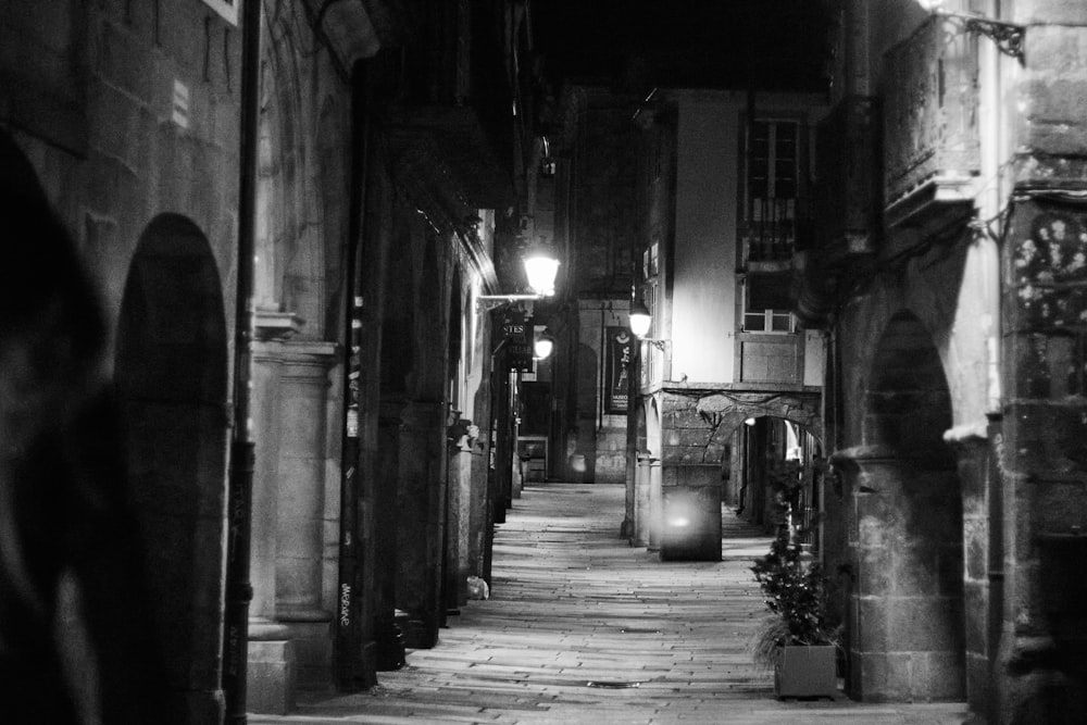 a dark alley way with a lamp on the side of it