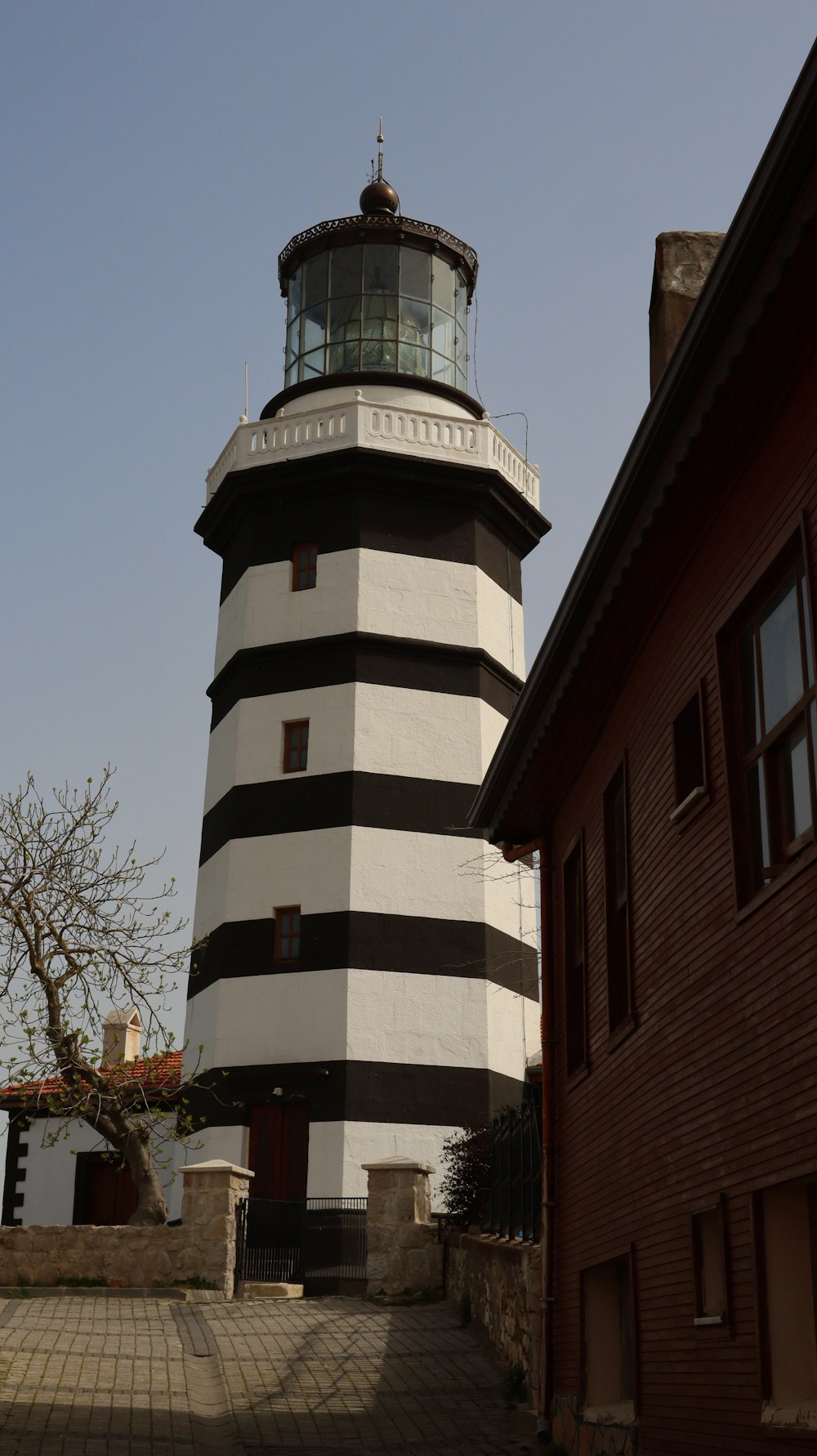 a large white and black lighthouse next to a building
