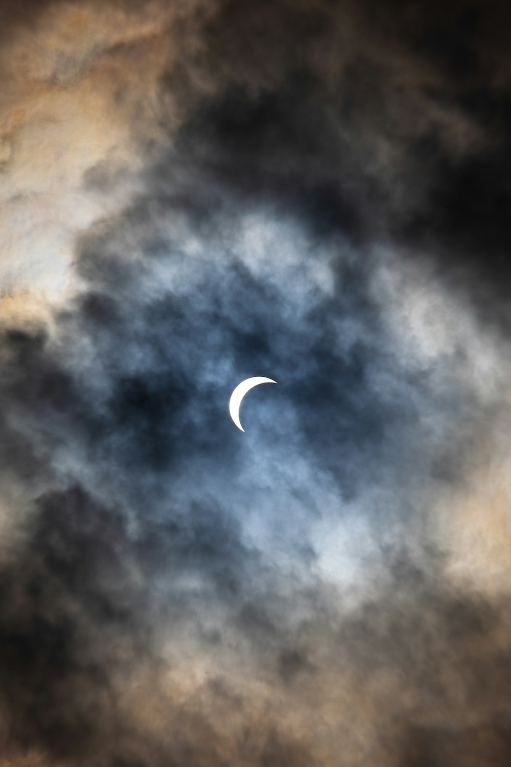 the moon is seen through a cloudy sky