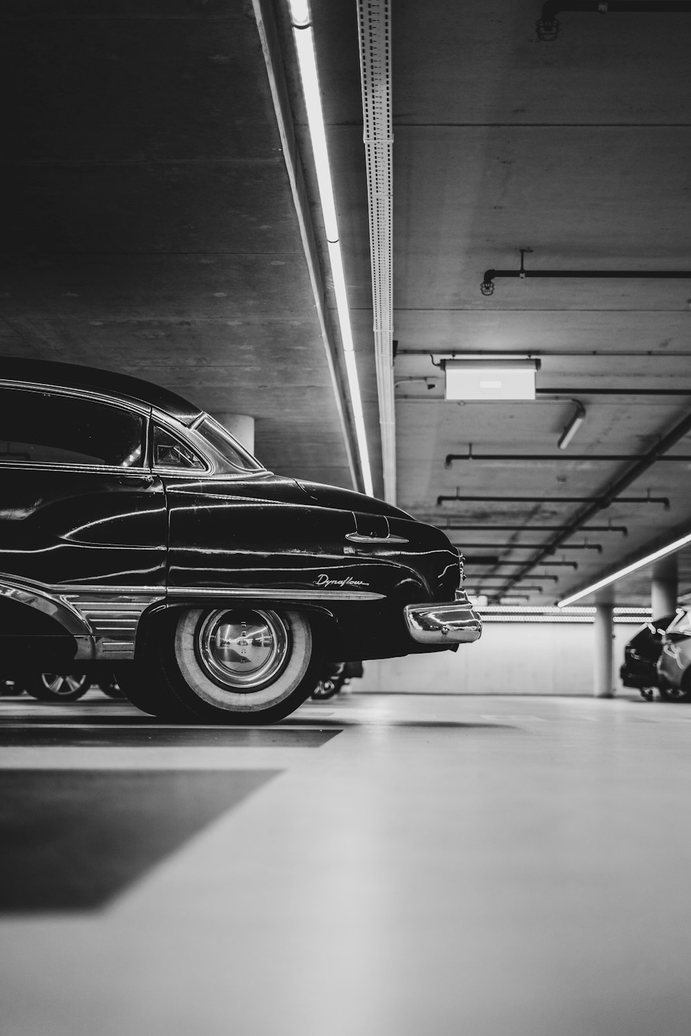 a black and white photo of a car in a parking garage