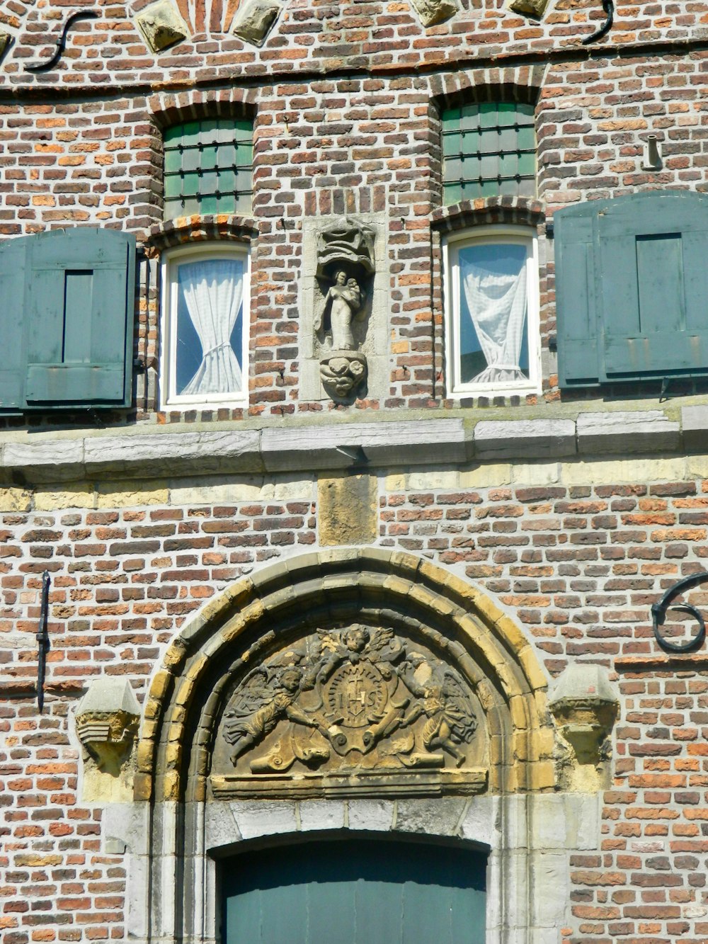 a brick building with green shutters and a green door