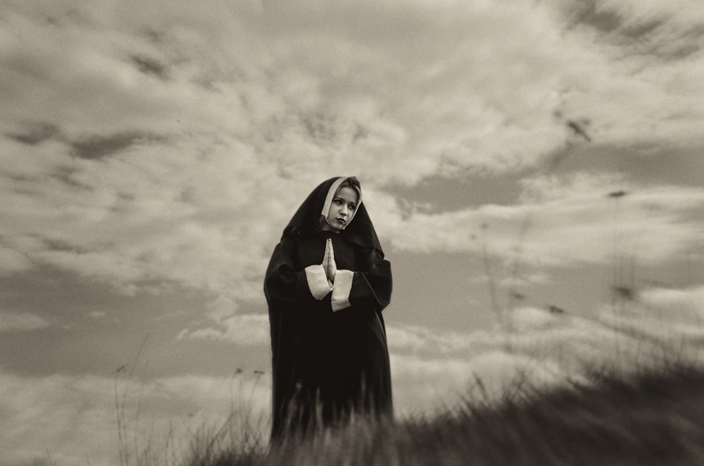 a woman in a nun costume standing in a field