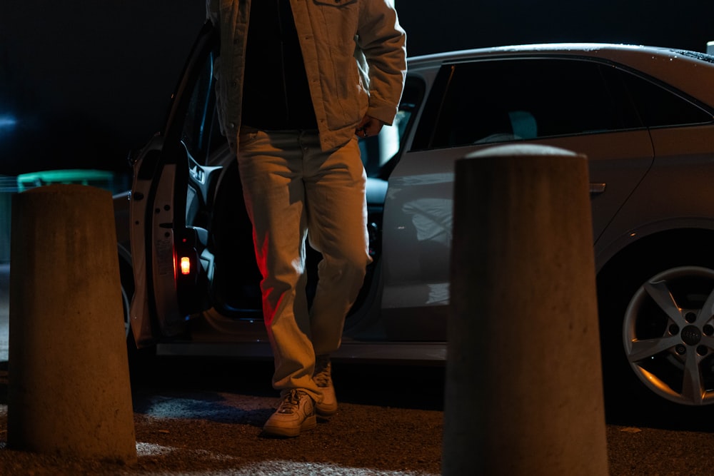 a man walking towards a car at night