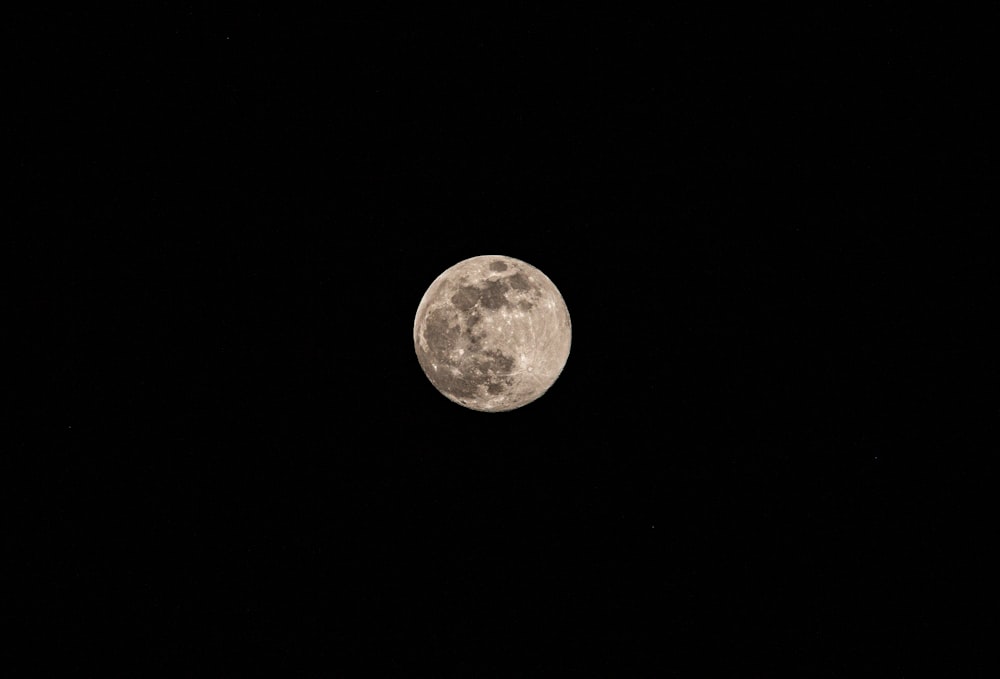 a full moon is seen in the dark sky