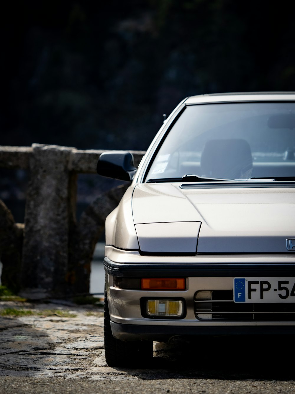 a white car parked next to a stone wall