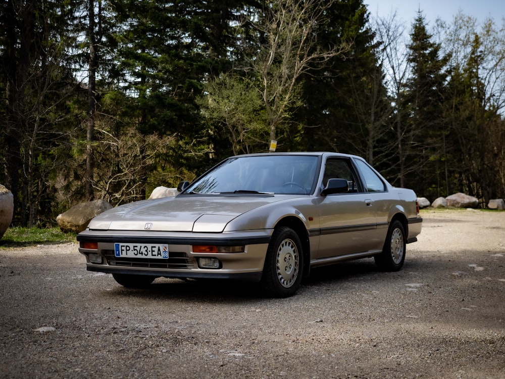 a silver car parked in front of some trees