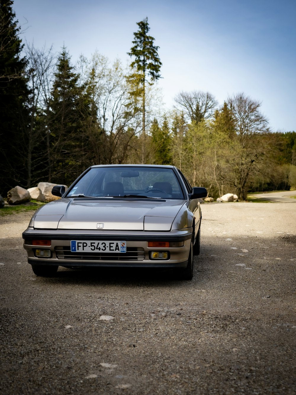 a car parked in a parking lot next to a forest