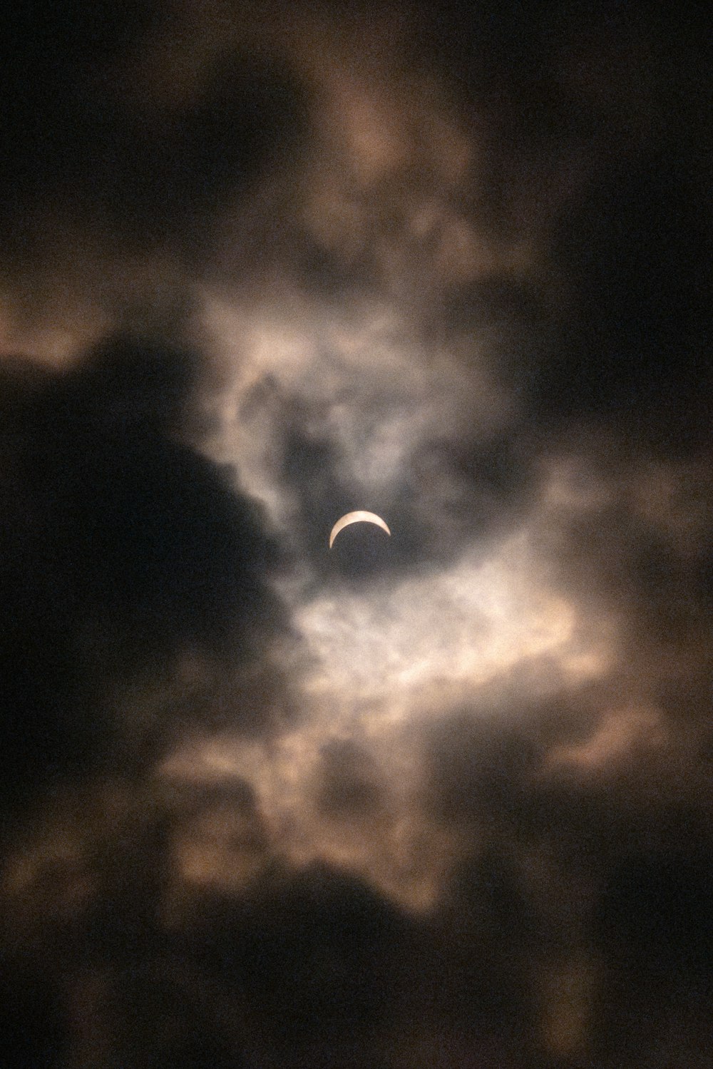 the moon is seen through a cloudy sky