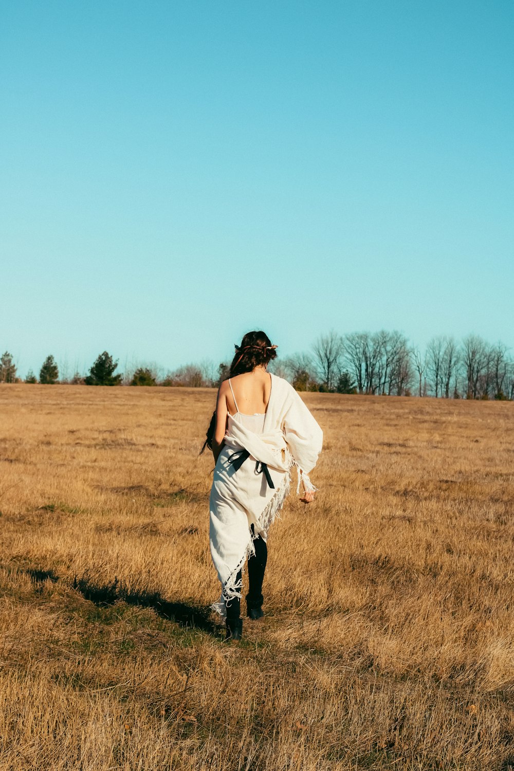 a woman walking through a dry grass field