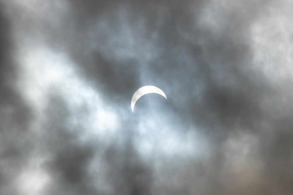 the moon is seen through a cloudy sky