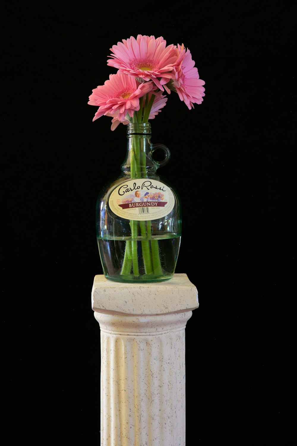 a vase filled with pink flowers sitting on top of a pedestal