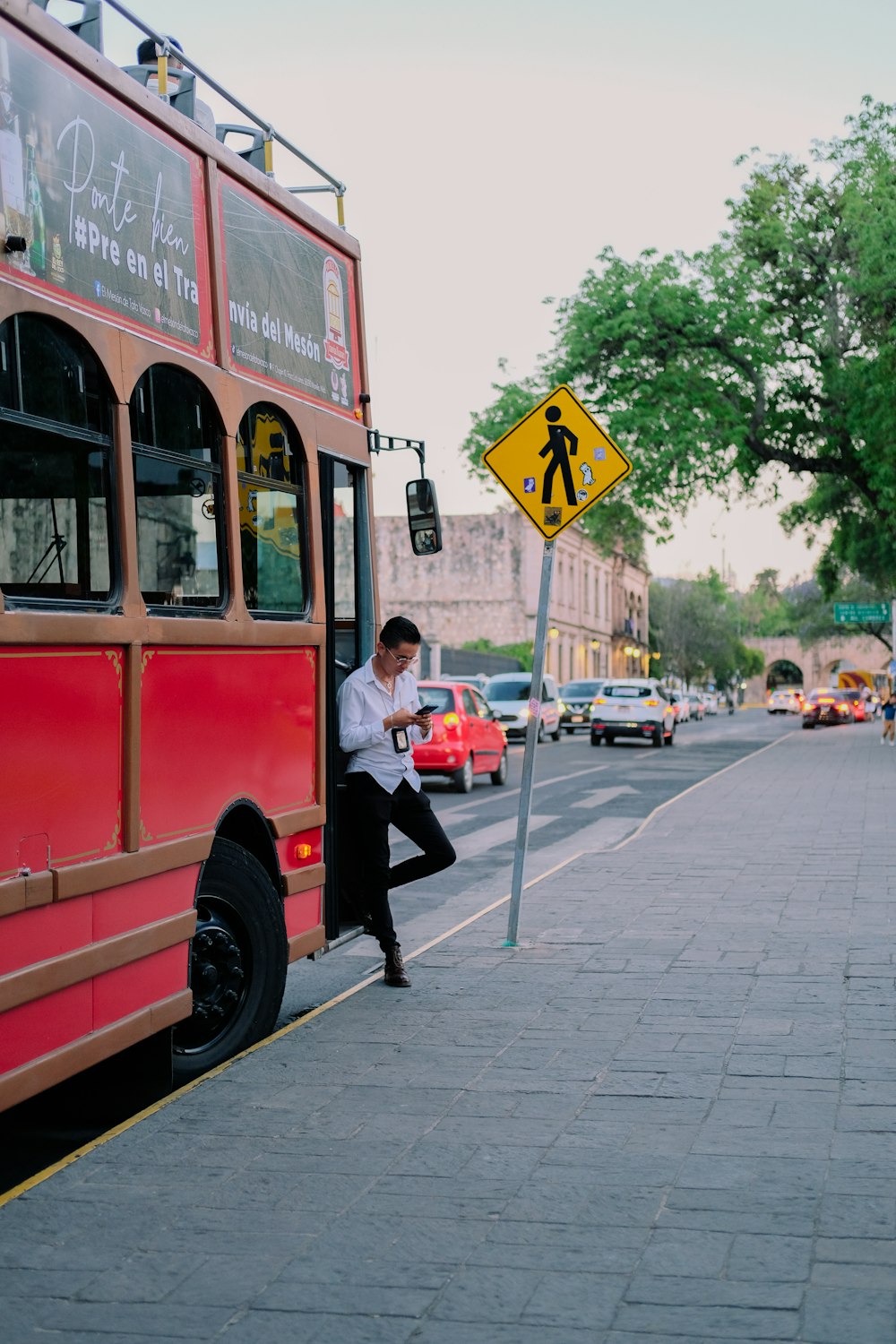 un uomo appoggiato a un palo accanto a un autobus rosso
