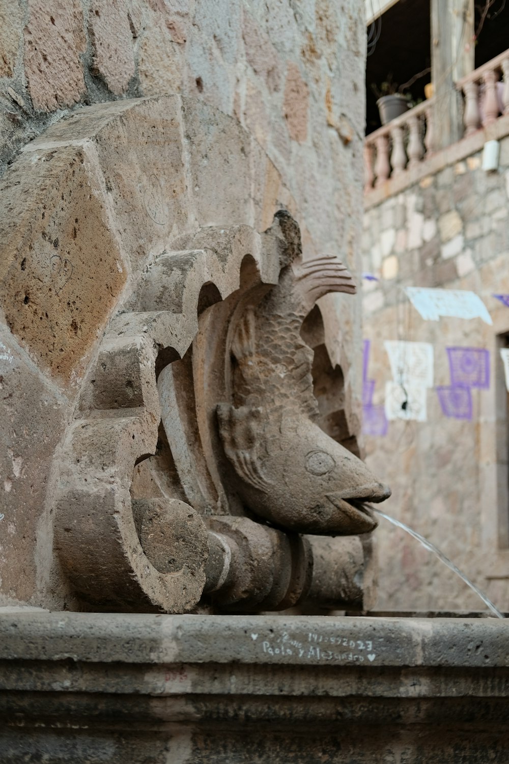 une statue d’un poisson sur un mur de pierre