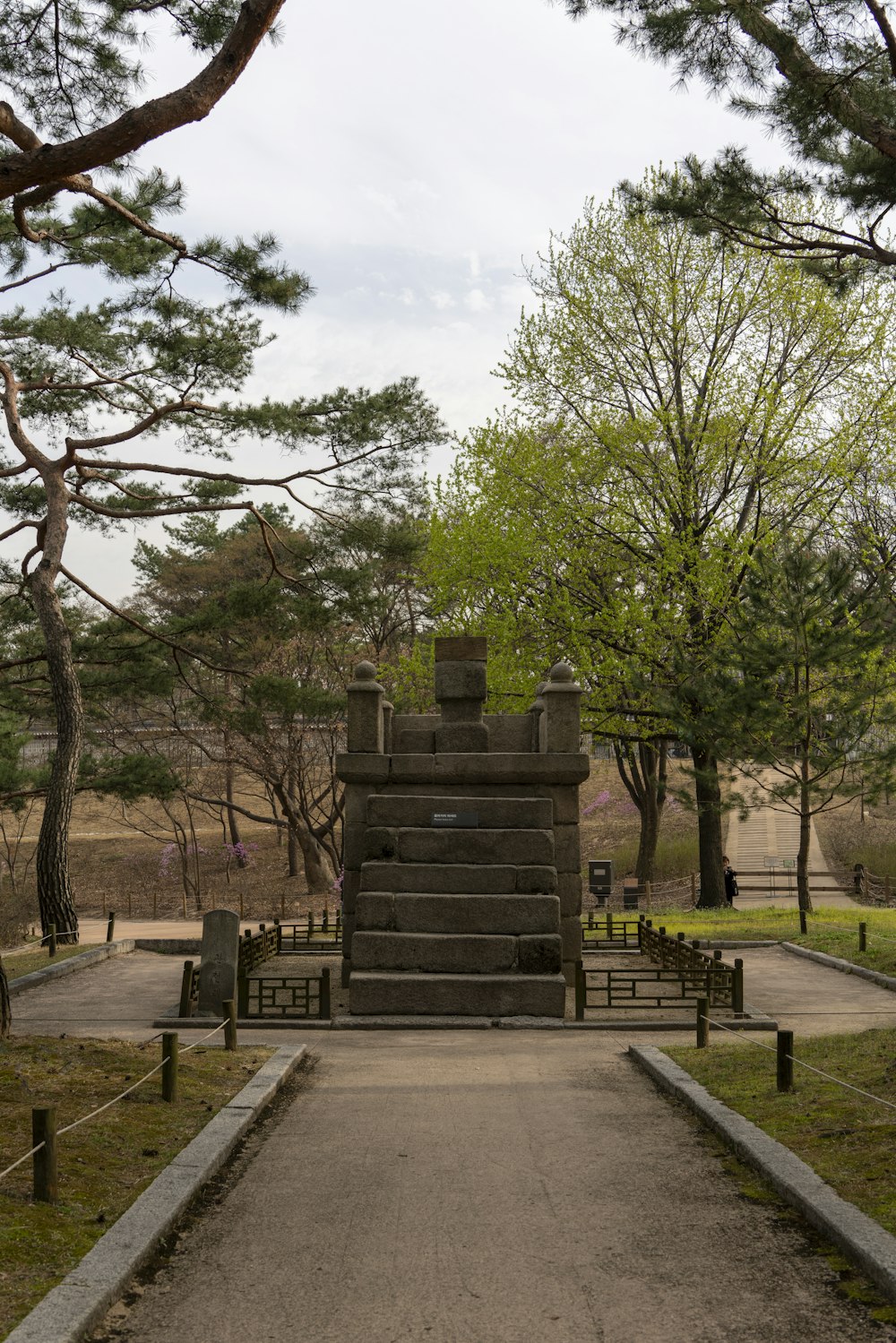 a stone monument in a park surrounded by trees