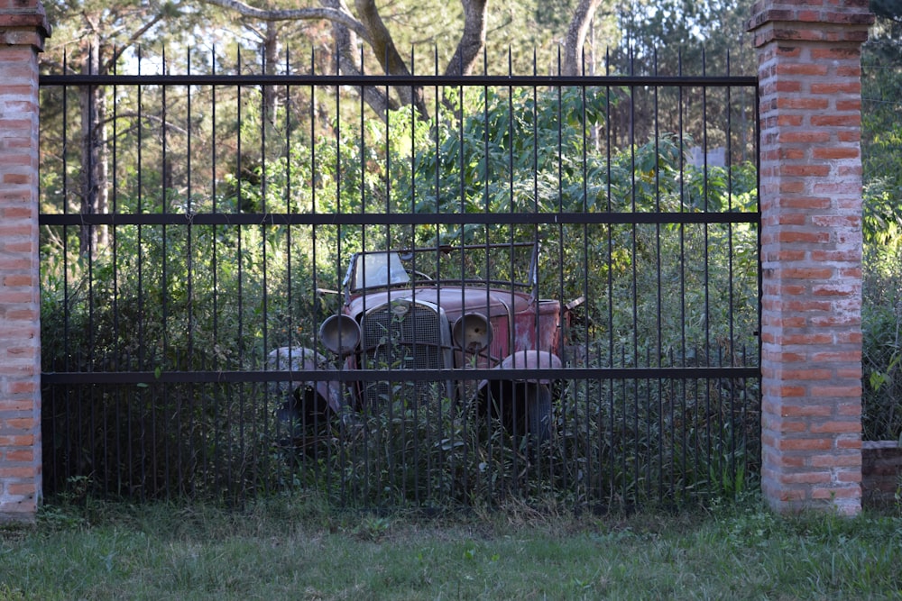 an old car behind a fence in a field