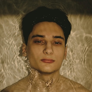 a man in a pool of water with a necklace around his neck