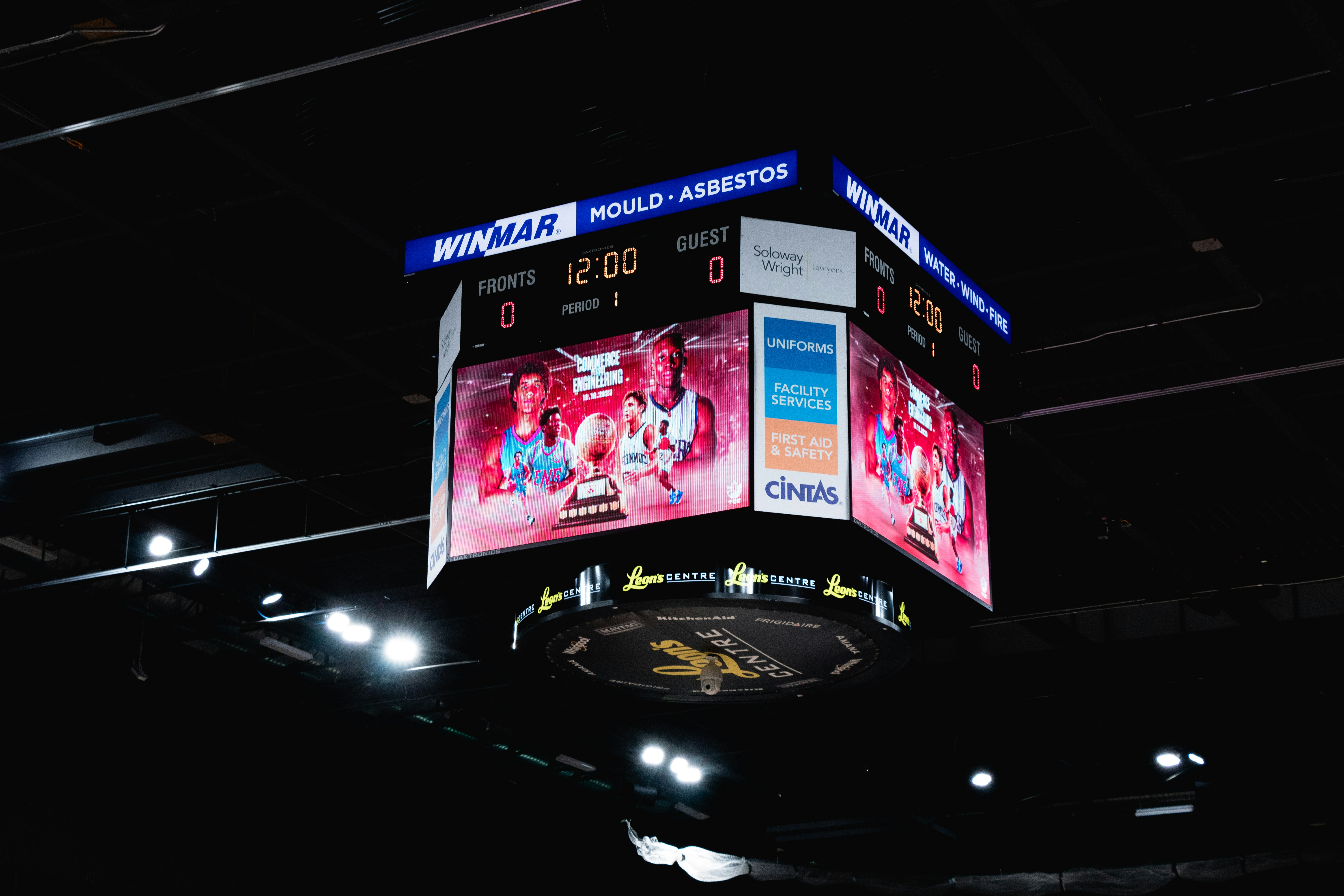 Público en una arena de baloncesto mirando el marcador durante un partido apretado