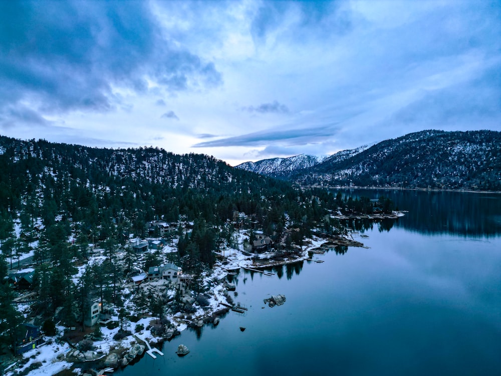 a lake surrounded by snow covered mountains under a cloudy sky