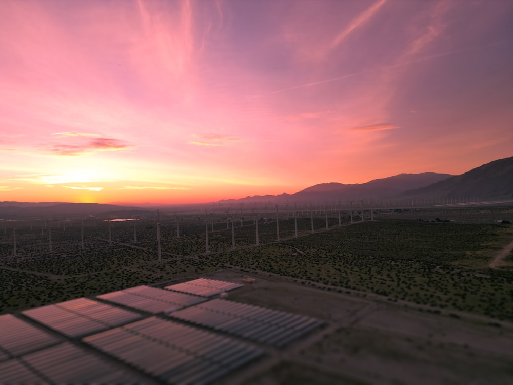 the sun is setting over a field of wind turbines