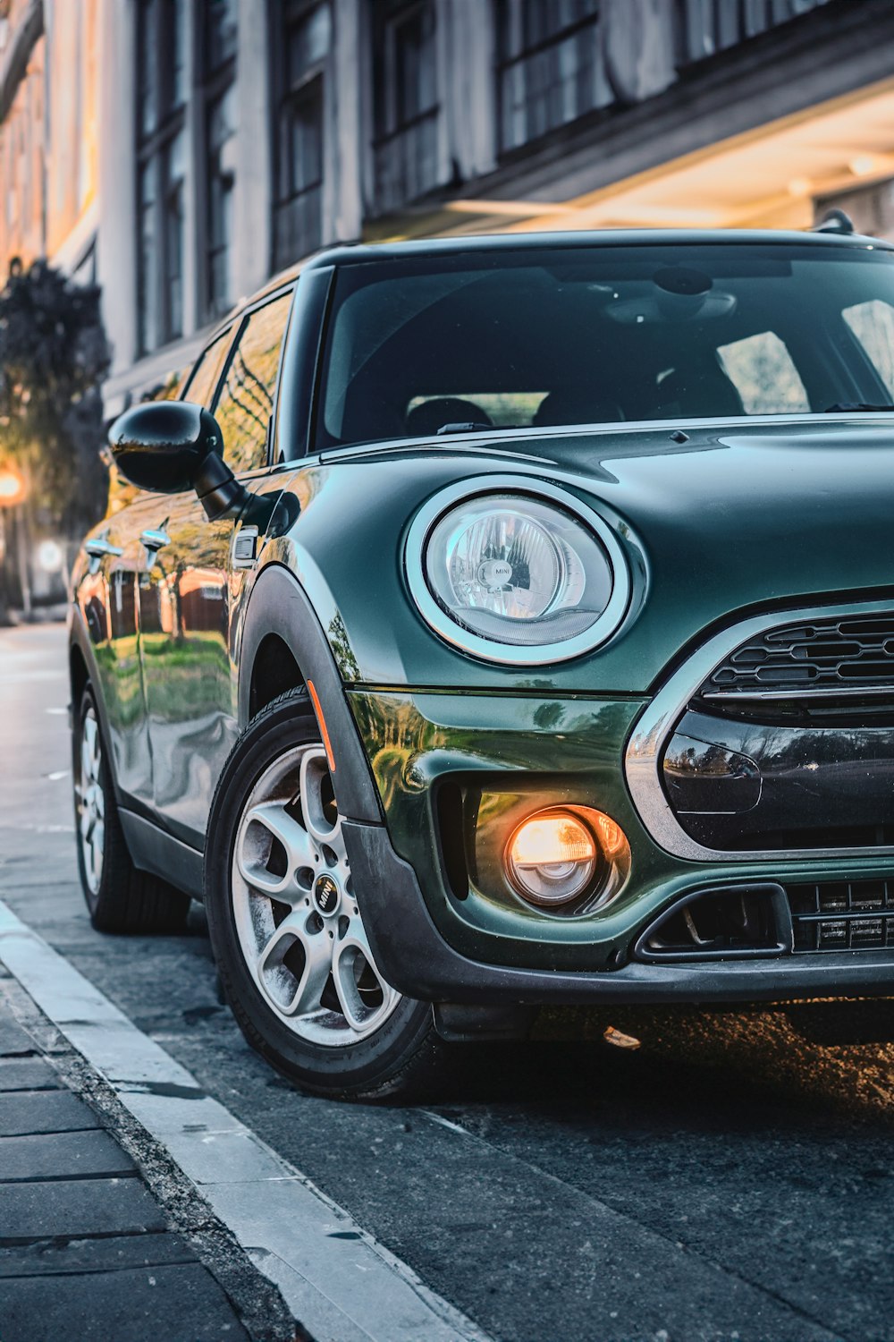 a green mini cooper parked on the side of the road