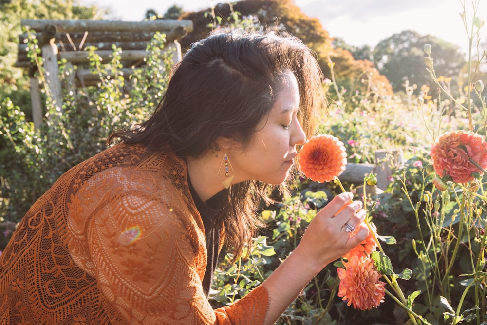 una mujer oliendo una flor en un jardín