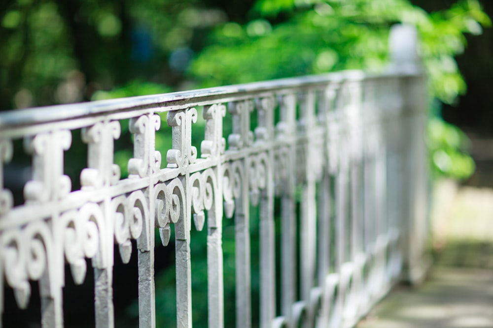 a close up of a metal fence with trees in the background