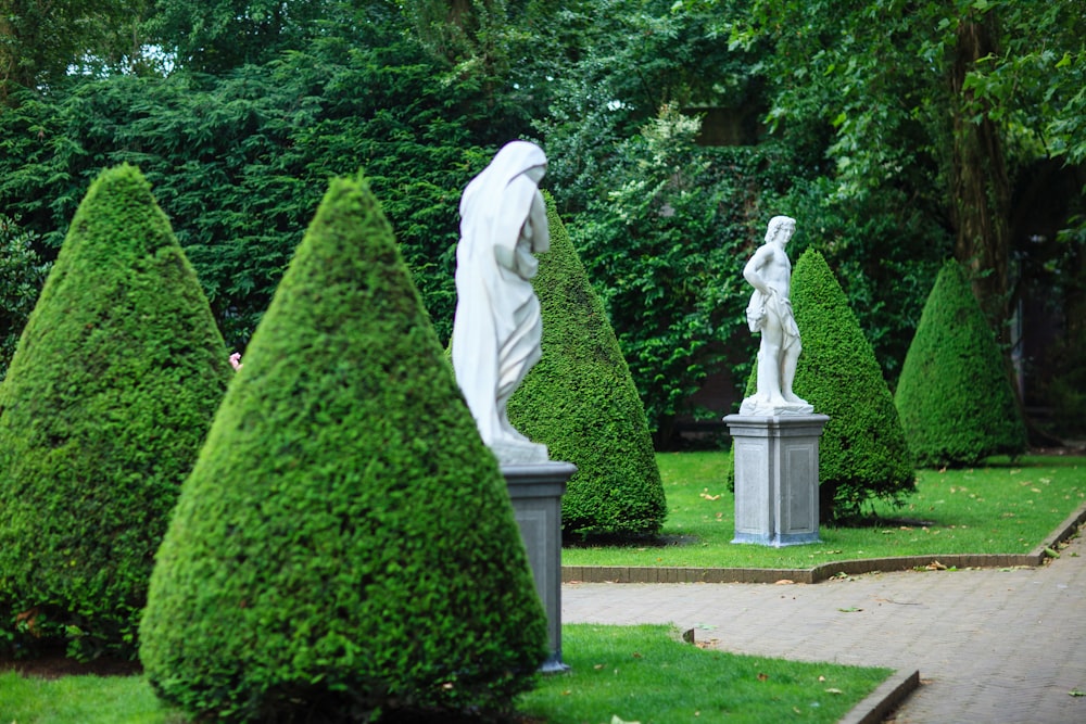 a group of statues sitting in the middle of a lush green park