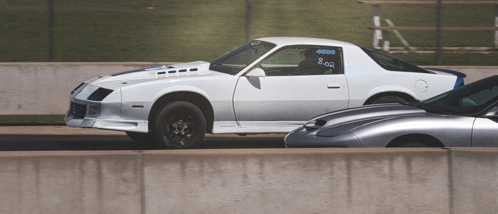 a white car and a silver car on a road