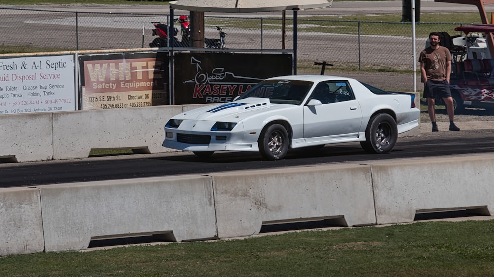 a white sports car driving down a race track