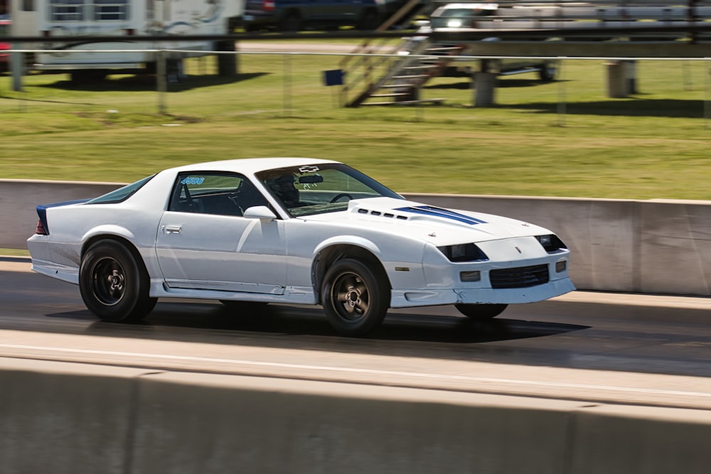 a white sports car driving down a road