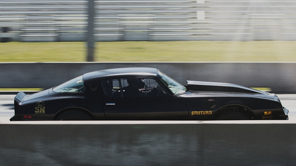 a black car driving down a race track