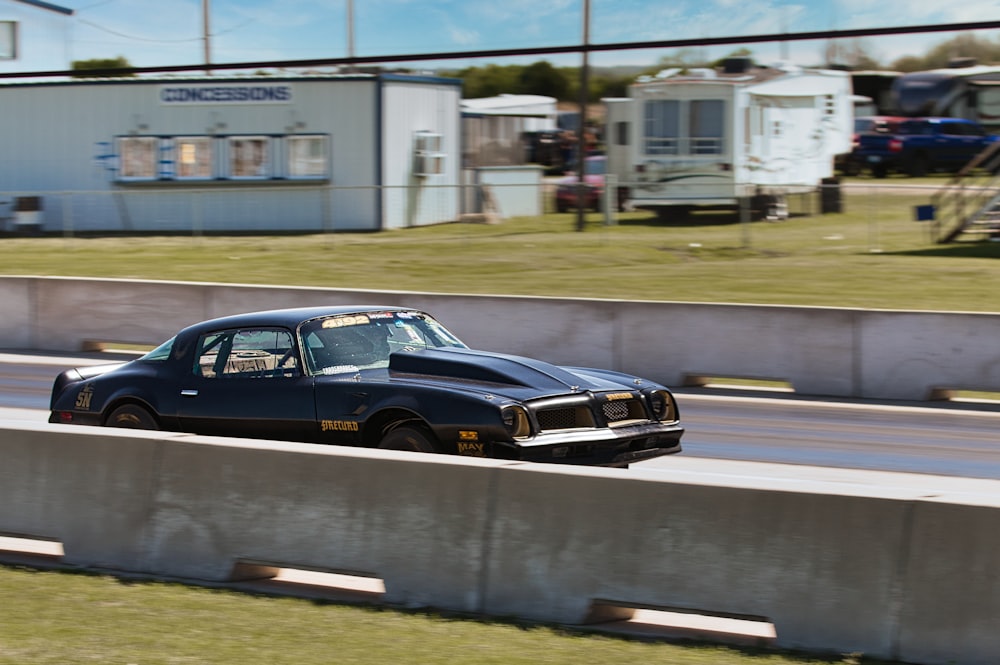 a black car driving down a road next to a building