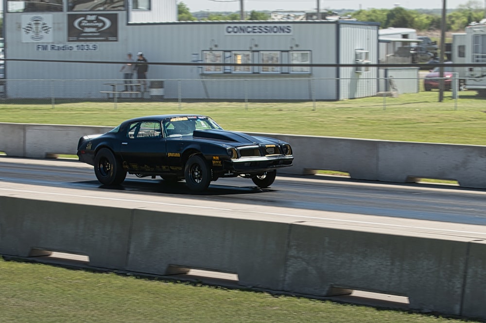 a black muscle car driving down a race track