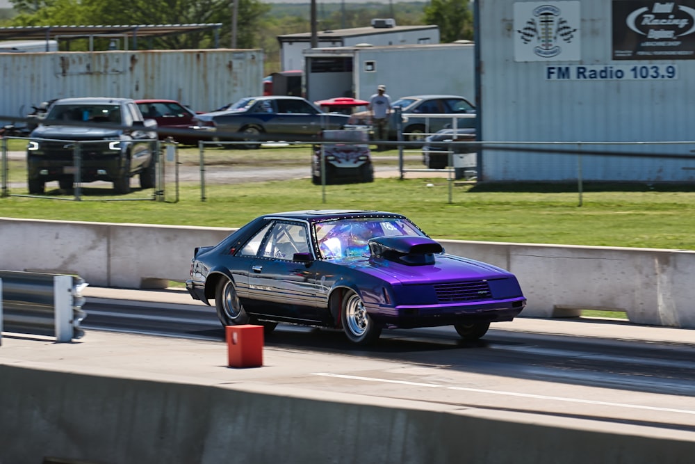 a purple car driving down a road next to a building