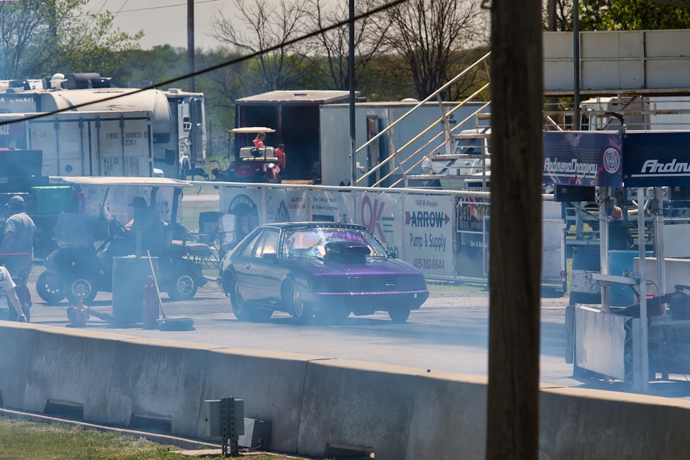 a purple car driving down a street next to a gas station