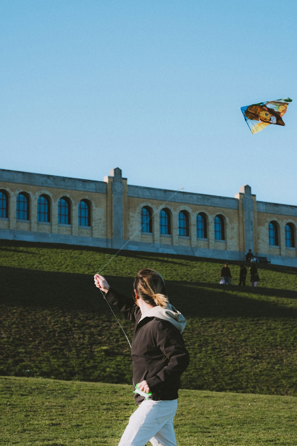 a woman is flying a kite in a field