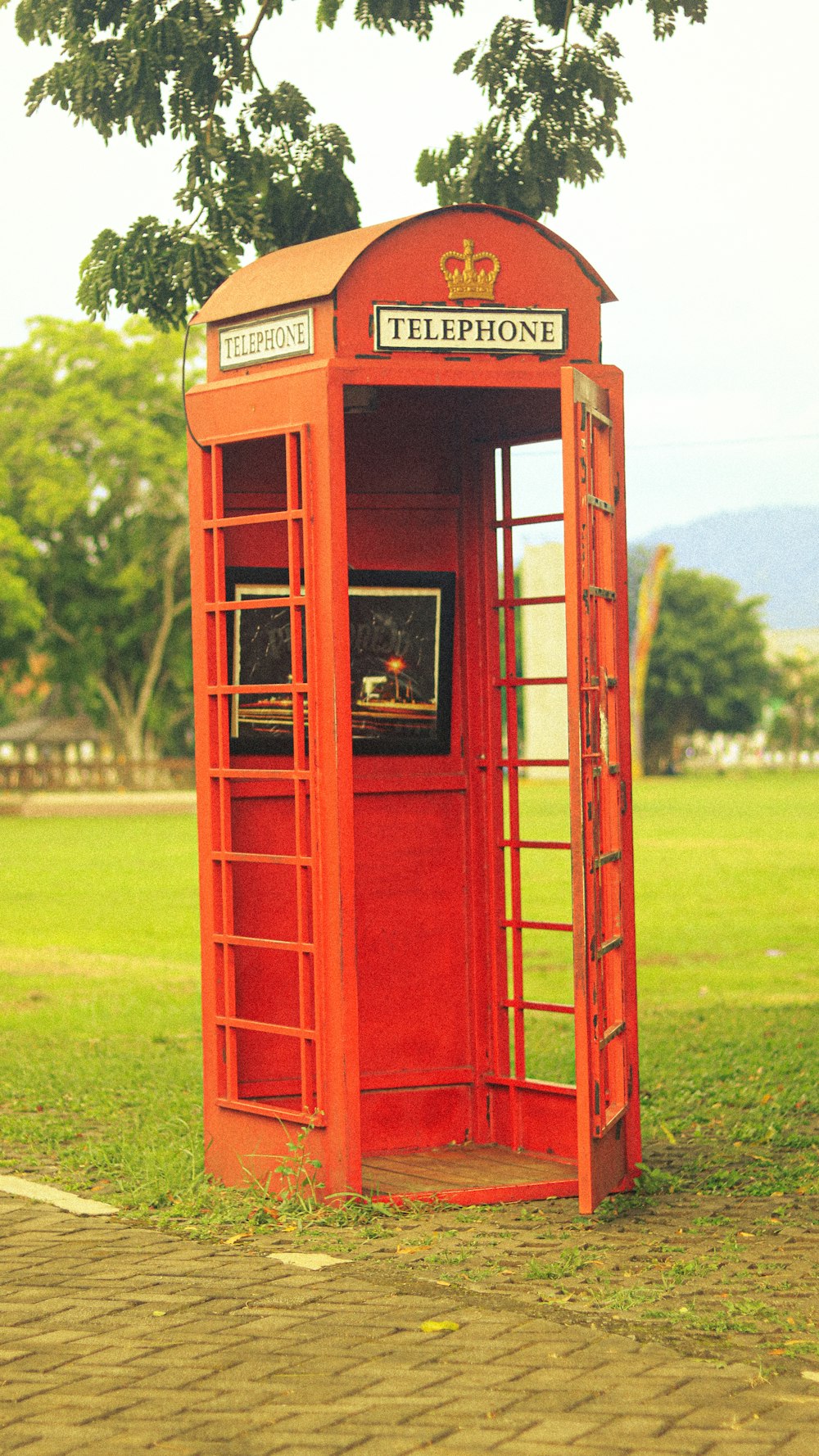a red phone booth sitting on top of a lush green field