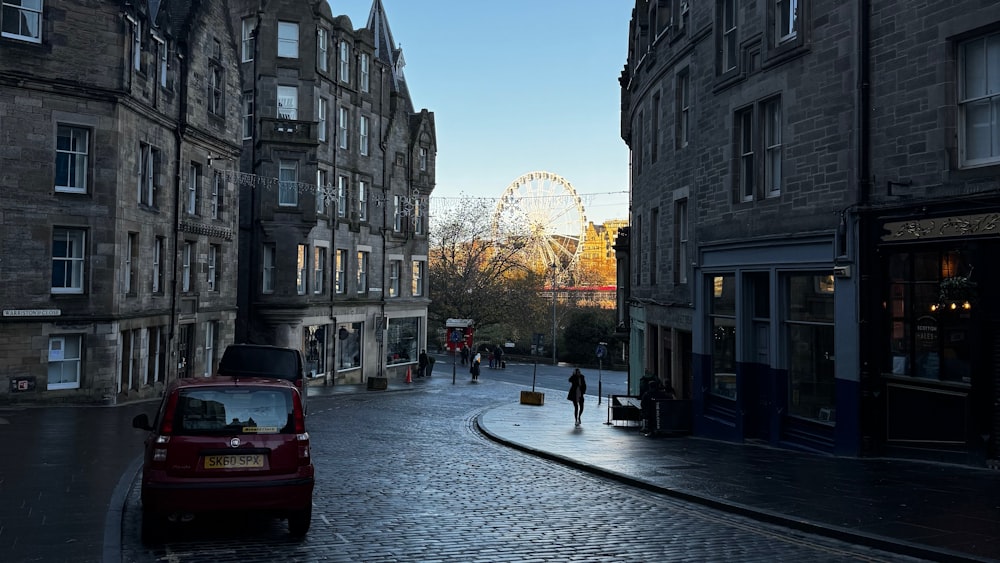 a red car is parked on a cobblestone street